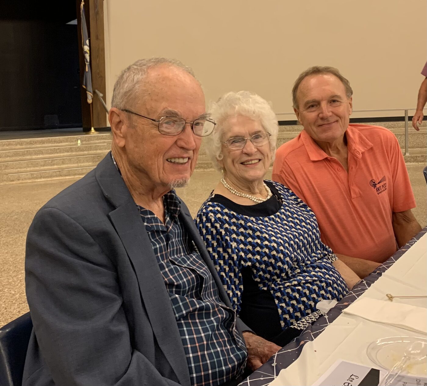 Three smiling guests seated at a decorated banquet table.