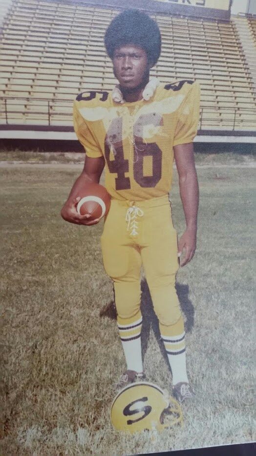 Vintage photo of a young football player in a gold uniform standing on a field.
