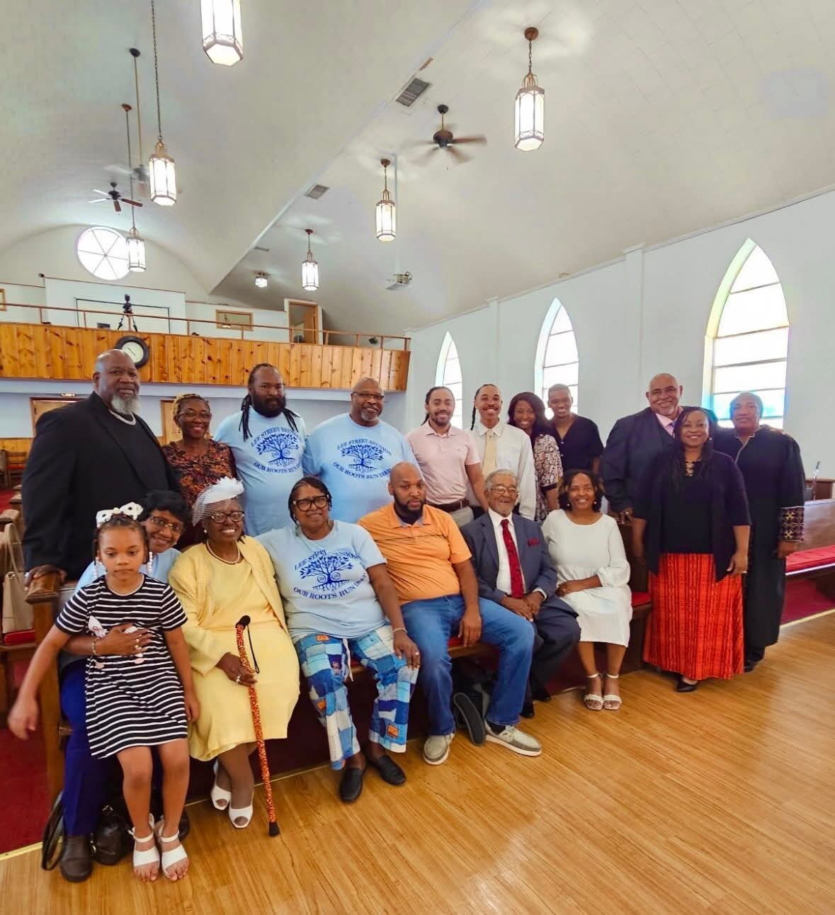 A large multigenerational group poses together inside a bright church sanctuary.