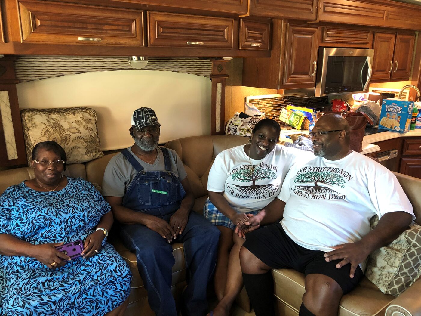 Four family members relax on a couch, two wearing Lee Street Reunion shirts.
