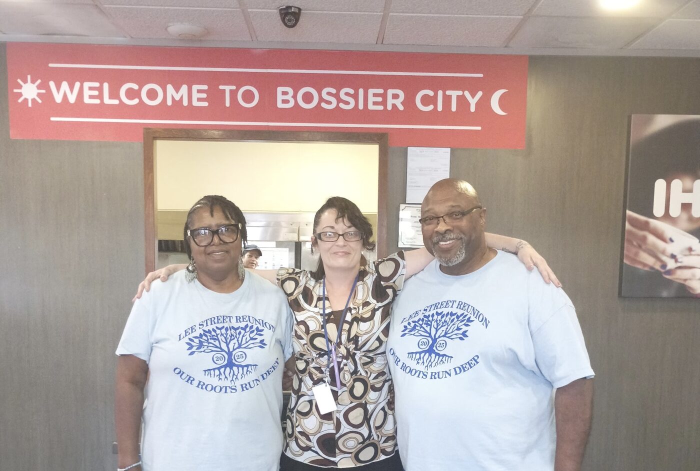 Three people in Lee Street Reunion shirts pose together at a restaurant counter.