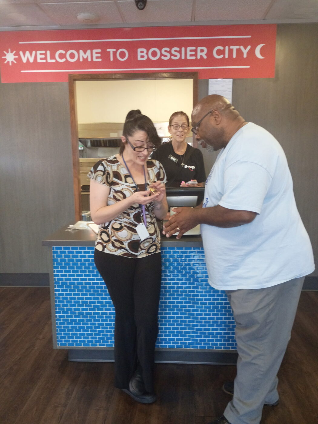 Two people admire a small gift at a restaurant front counter.
