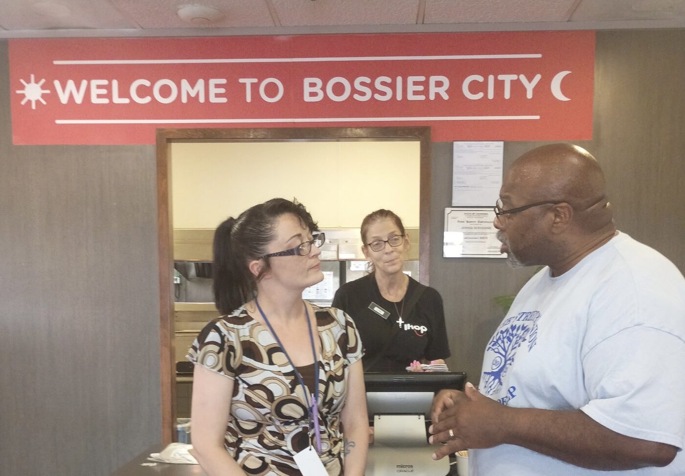 Visitors chat with staff at a restaurant welcome counter.